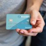 Dreamfolks Airport Lounge Access Card: A person holding a credit card that grants access to airport lounges through Dreamfolks.